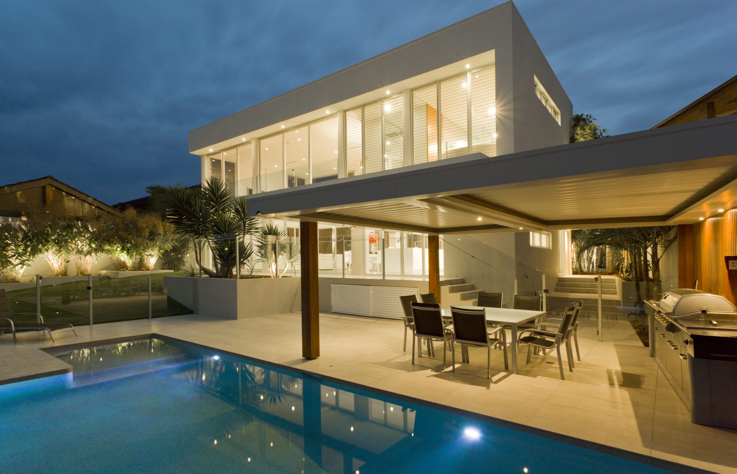 Modern,House,At,Dusk,With,Swimming,Pool,And,Barbecue,In